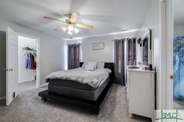 bedroom featuring carpet, ceiling fan, a spacious closet, and a textured ceiling