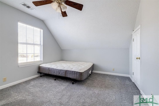 carpeted bedroom with multiple windows, a textured ceiling, vaulted ceiling, and ceiling fan