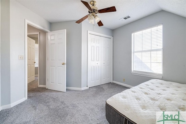 bedroom featuring carpet flooring, ceiling fan, lofted ceiling, a textured ceiling, and a closet