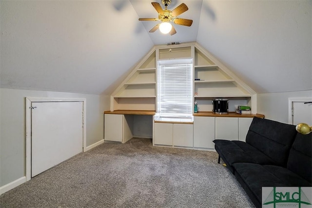 additional living space with light carpet, built in shelves, vaulted ceiling, and ceiling fan