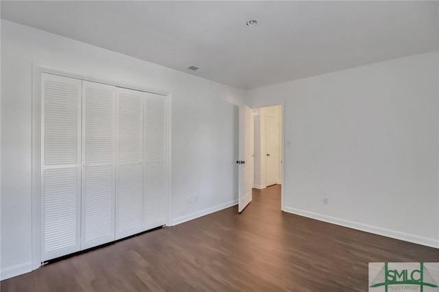 unfurnished bedroom with dark hardwood / wood-style floors and a closet