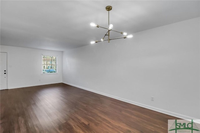 empty room with dark hardwood / wood-style flooring and a chandelier