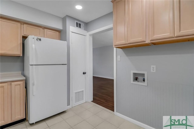 kitchen with light brown cabinets, white fridge, and light tile patterned floors