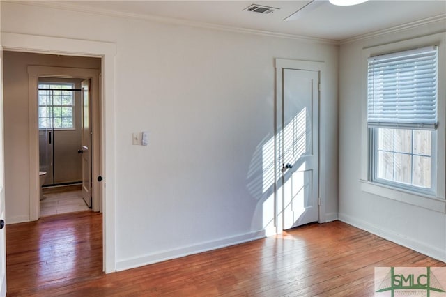 spare room featuring wood-type flooring and crown molding