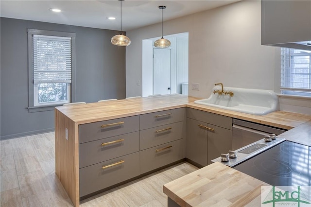 kitchen with decorative light fixtures, gray cabinets, kitchen peninsula, and a healthy amount of sunlight