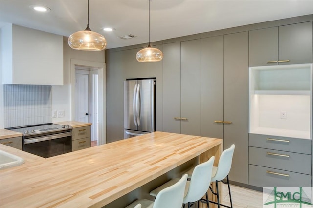 kitchen with a kitchen bar, kitchen peninsula, gray cabinetry, stainless steel appliances, and pendant lighting