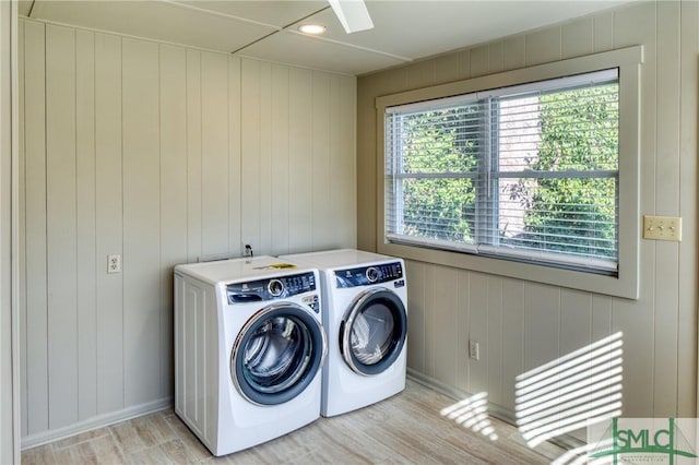 laundry room featuring washer and clothes dryer, wood walls, and light hardwood / wood-style flooring