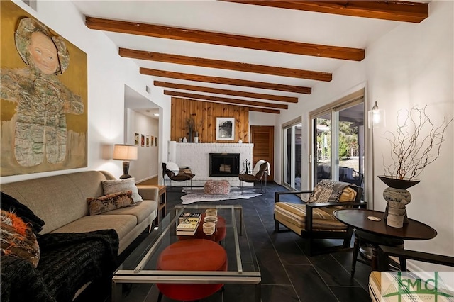 living room featuring beam ceiling, a fireplace, and wooden walls