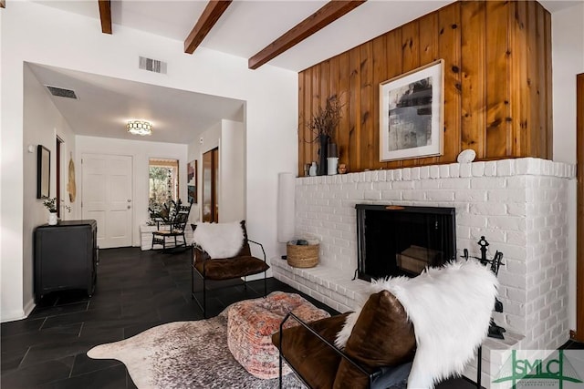 living room featuring beamed ceiling, a brick fireplace, and wooden walls