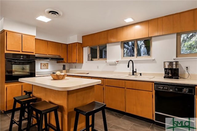 kitchen with a kitchen bar, sink, dark tile patterned floors, and black appliances