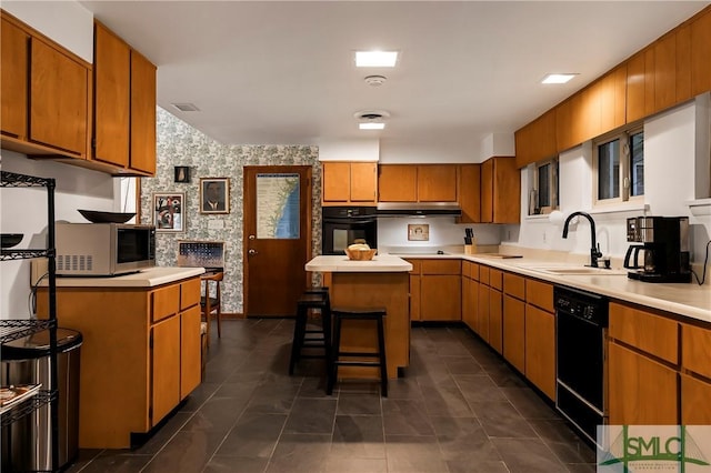 kitchen with a kitchen breakfast bar, sink, a kitchen island, and black appliances