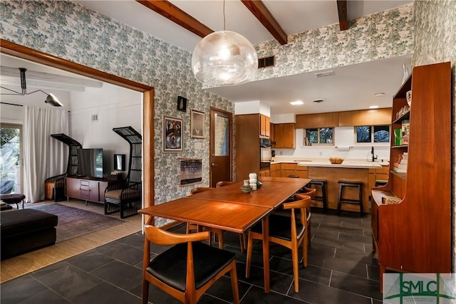 dining room featuring beam ceiling and dark tile patterned flooring