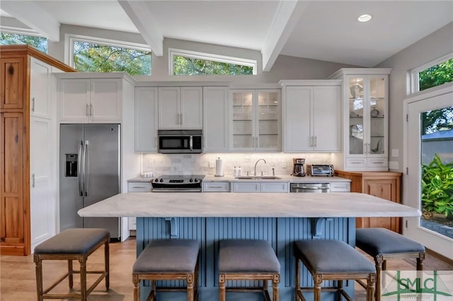 kitchen with vaulted ceiling with beams, white cabinetry, sink, and appliances with stainless steel finishes