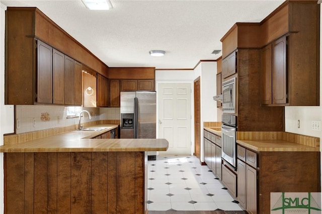 kitchen with decorative backsplash, kitchen peninsula, sink, and appliances with stainless steel finishes