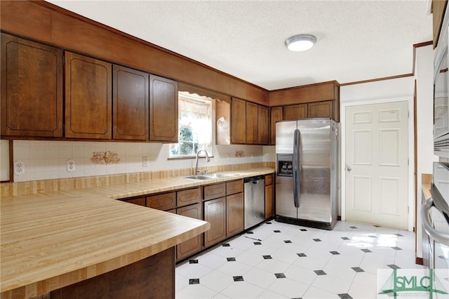 kitchen featuring butcher block countertops, sink, stainless steel appliances, and a textured ceiling