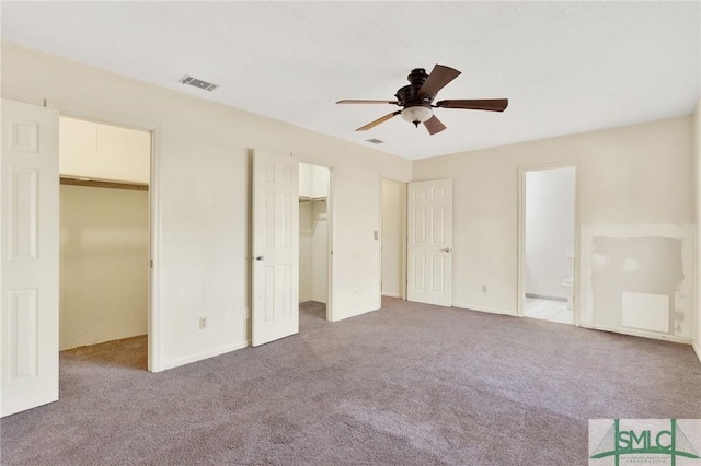 unfurnished bedroom featuring carpet flooring, ceiling fan, and a spacious closet