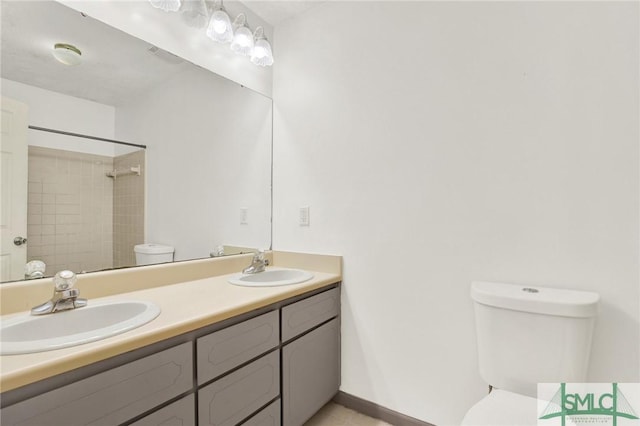 bathroom featuring tiled shower, vanity, and toilet