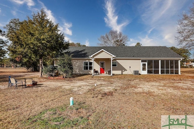 ranch-style home with central air condition unit, a fire pit, and a sunroom