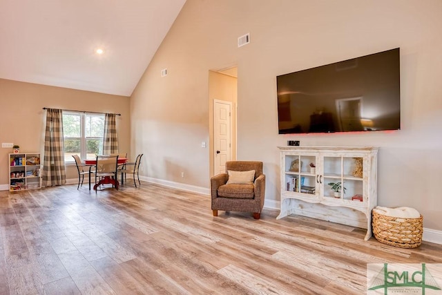 sitting room with high vaulted ceiling and light hardwood / wood-style flooring