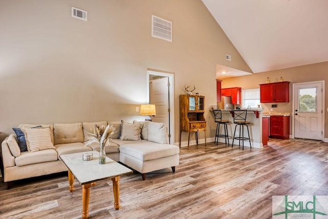 living room featuring high vaulted ceiling and wood-type flooring