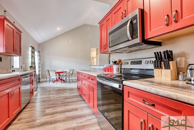 kitchen with stainless steel appliances, light wood-type flooring, and vaulted ceiling