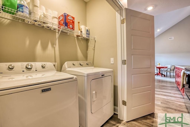 clothes washing area with hardwood / wood-style flooring and separate washer and dryer