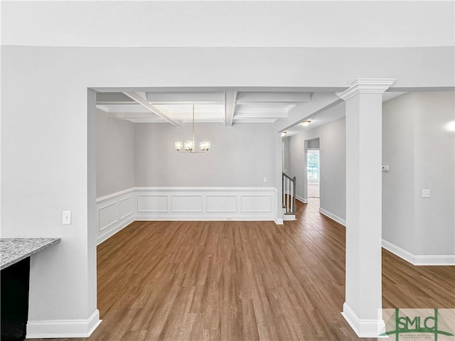 unfurnished dining area with hardwood / wood-style floors, beamed ceiling, coffered ceiling, and a notable chandelier