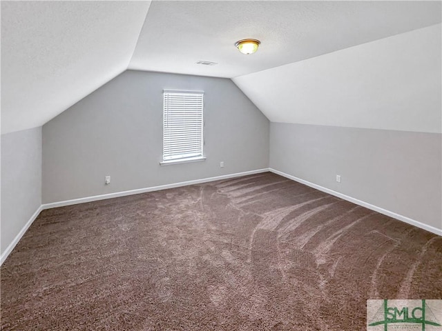 bonus room with a textured ceiling, vaulted ceiling, and dark carpet