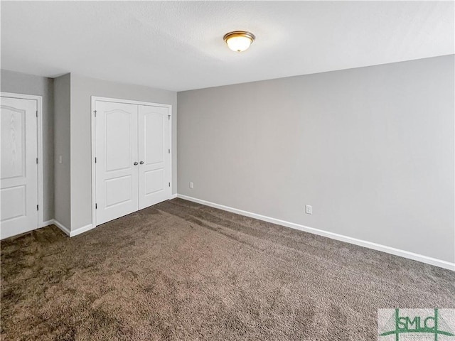 unfurnished bedroom with dark colored carpet and a closet