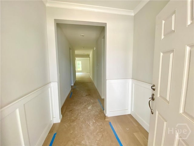 hall featuring a wainscoted wall, a decorative wall, and crown molding