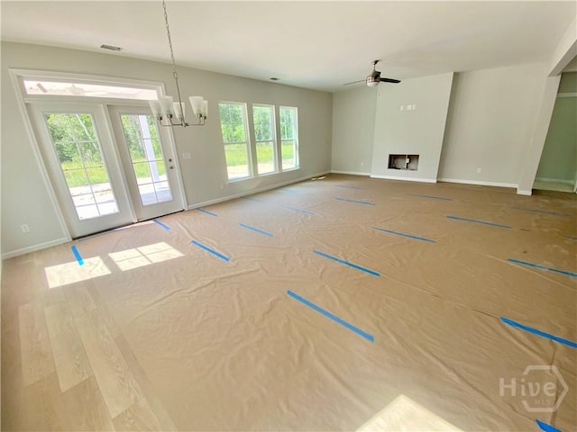 unfurnished living room featuring a chandelier, baseboards, and ceiling fan