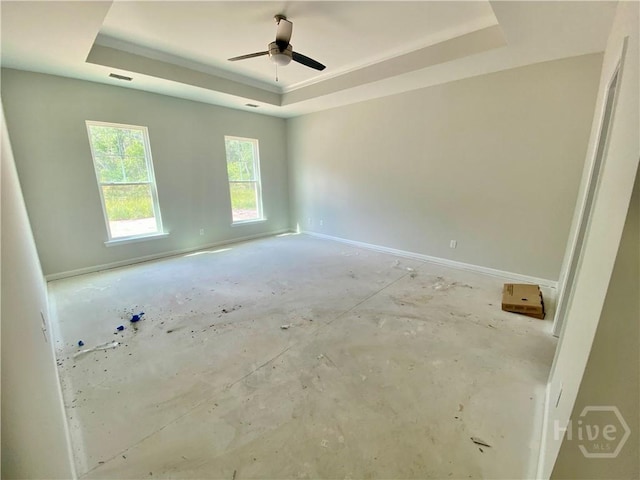 spare room with a tray ceiling, a ceiling fan, and baseboards