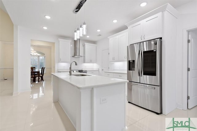 kitchen featuring stainless steel fridge, wall chimney range hood, light tile patterned floors, a center island with sink, and white cabinets