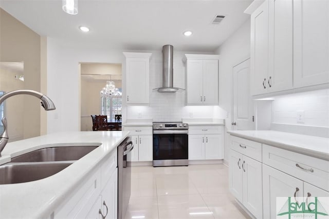 kitchen featuring white cabinetry, sink, wall chimney exhaust hood, hanging light fixtures, and appliances with stainless steel finishes