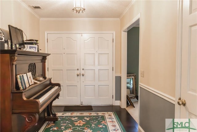 entryway featuring ornamental molding and a textured ceiling