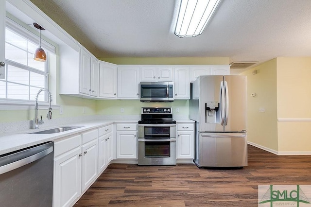 kitchen with dark wood-type flooring, white cabinets, sink, hanging light fixtures, and stainless steel appliances