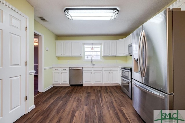 kitchen with stainless steel appliances, white cabinetry, and dark wood-type flooring