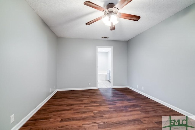 spare room with a textured ceiling, ceiling fan, and dark wood-type flooring