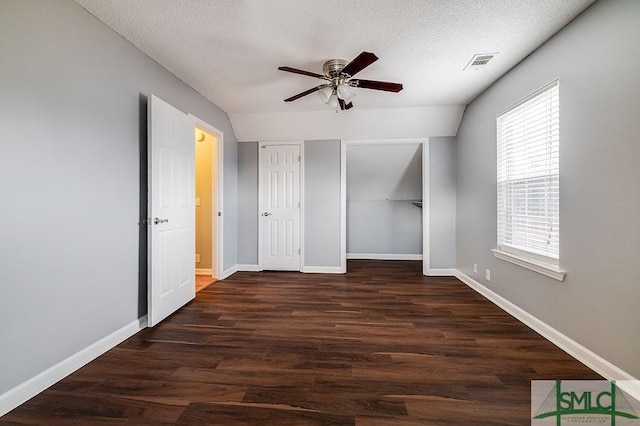 unfurnished bedroom with a textured ceiling, ceiling fan, lofted ceiling, and dark wood-type flooring