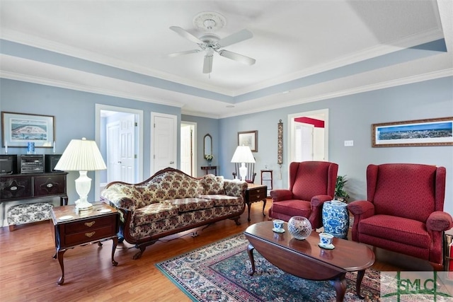 living room featuring ceiling fan, hardwood / wood-style floors, crown molding, and a tray ceiling