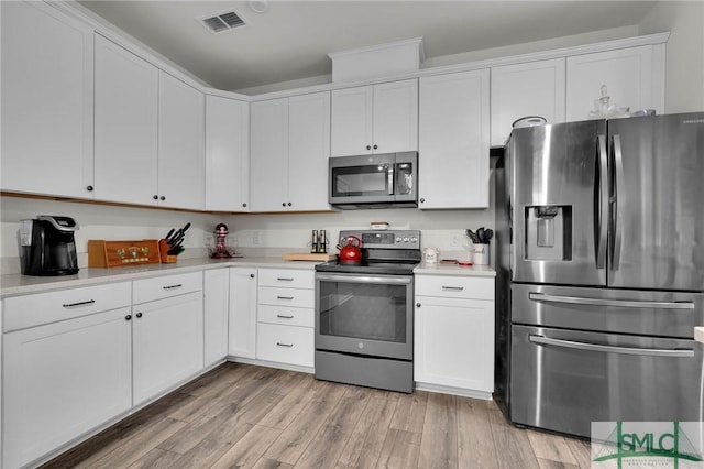 kitchen featuring stainless steel appliances, white cabinetry, and light hardwood / wood-style floors