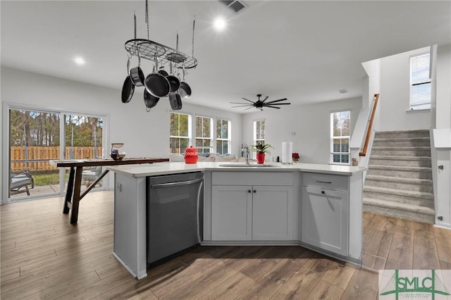 kitchen featuring sink, wood-type flooring, stainless steel dishwasher, and a center island with sink