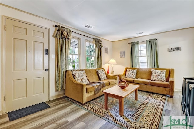 living room with crown molding and light wood-type flooring