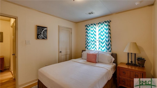 bedroom featuring light wood-type flooring and crown molding