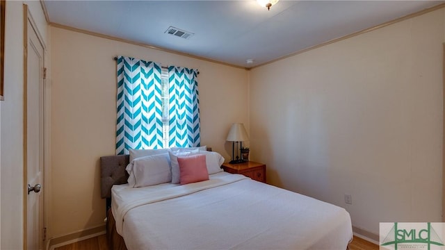 bedroom featuring wood-type flooring and ornamental molding