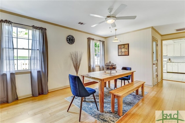 dining area featuring crown molding, plenty of natural light, ceiling fan, and light wood-type flooring