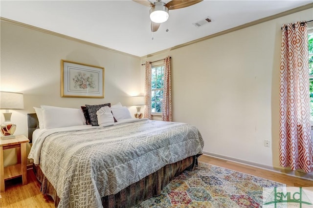 bedroom with ceiling fan, crown molding, and light hardwood / wood-style flooring