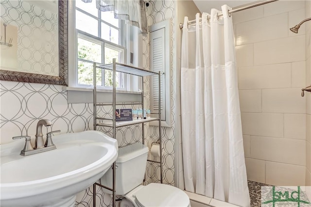 bathroom with toilet, sink, and a shower with shower curtain