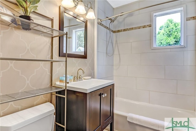 full bathroom featuring vanity, tiled shower / bath combo, and toilet