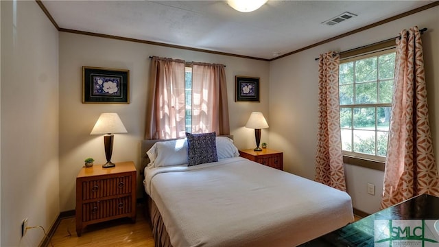 bedroom with ornamental molding, light hardwood / wood-style flooring, and multiple windows